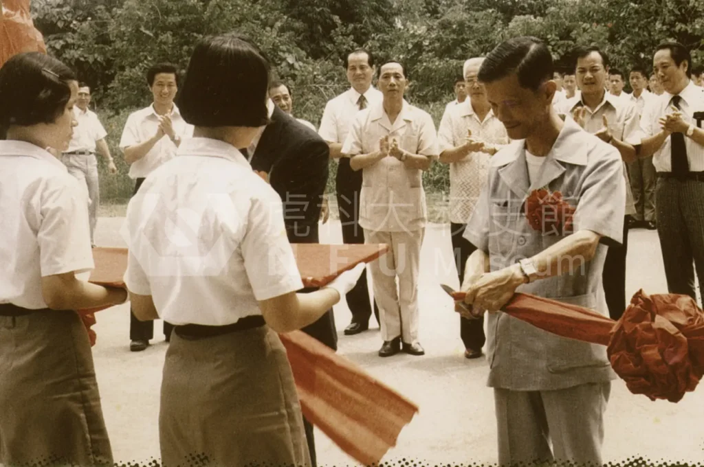 一個人正在剪綵，後面有一群人在鼓掌。